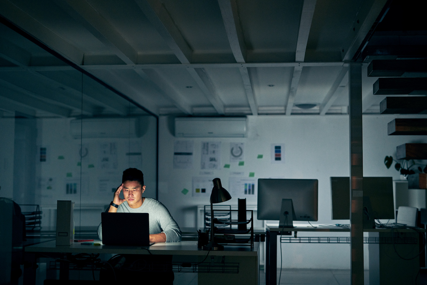IT support agent working late in a dark office, depicting job satisfaction and agent turnover