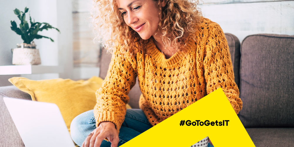 Woman in a yellow sweater working from the couch, reflecting the remote work trends of choice and flexibility