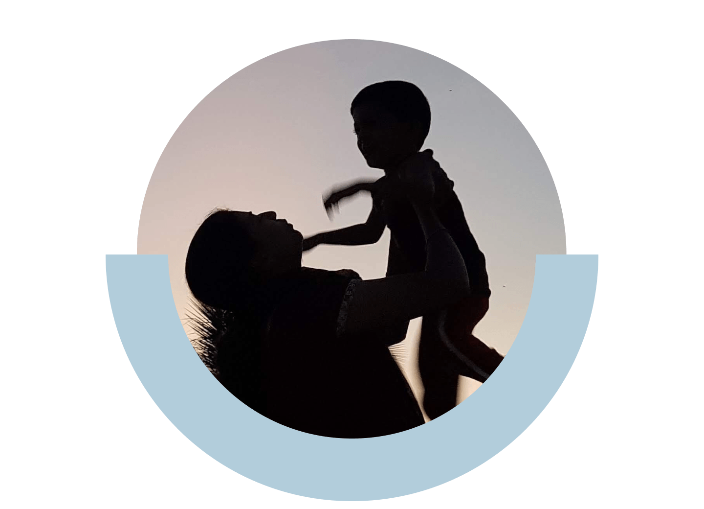 Eine Person hält ein Kleinkind, während im Hintergrund die Sonne untergeht.