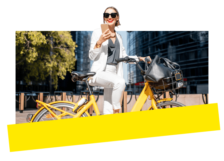 Professionista che riposa durante un giro in bicicletta, con lo sfondo dello skyline della città, mentre utilizza l'app mobile GoTo Connect per connettersi da qualsiasi luogo.