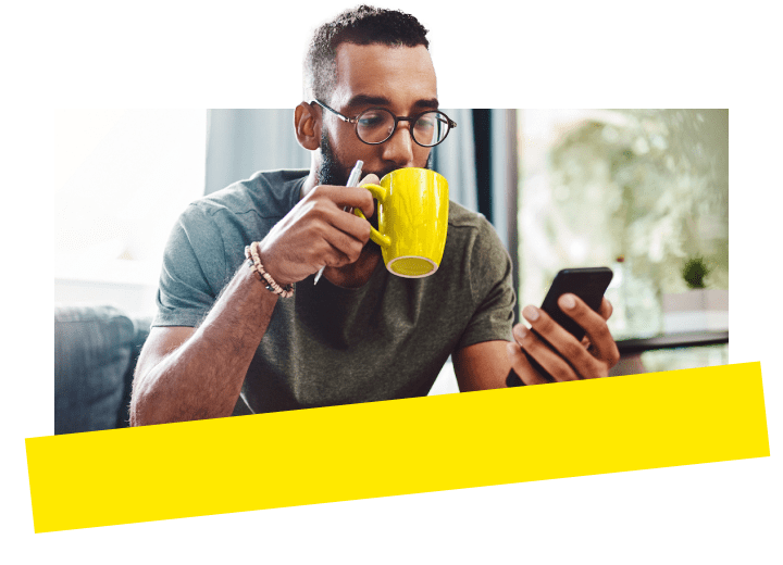 Man looking at phone while drinking coffee.