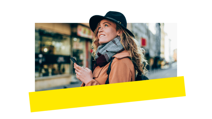 Eine Frau nutzt GoTo Connect auf ihrem Smartphone, während sie in der Stadt unterwegs ist.