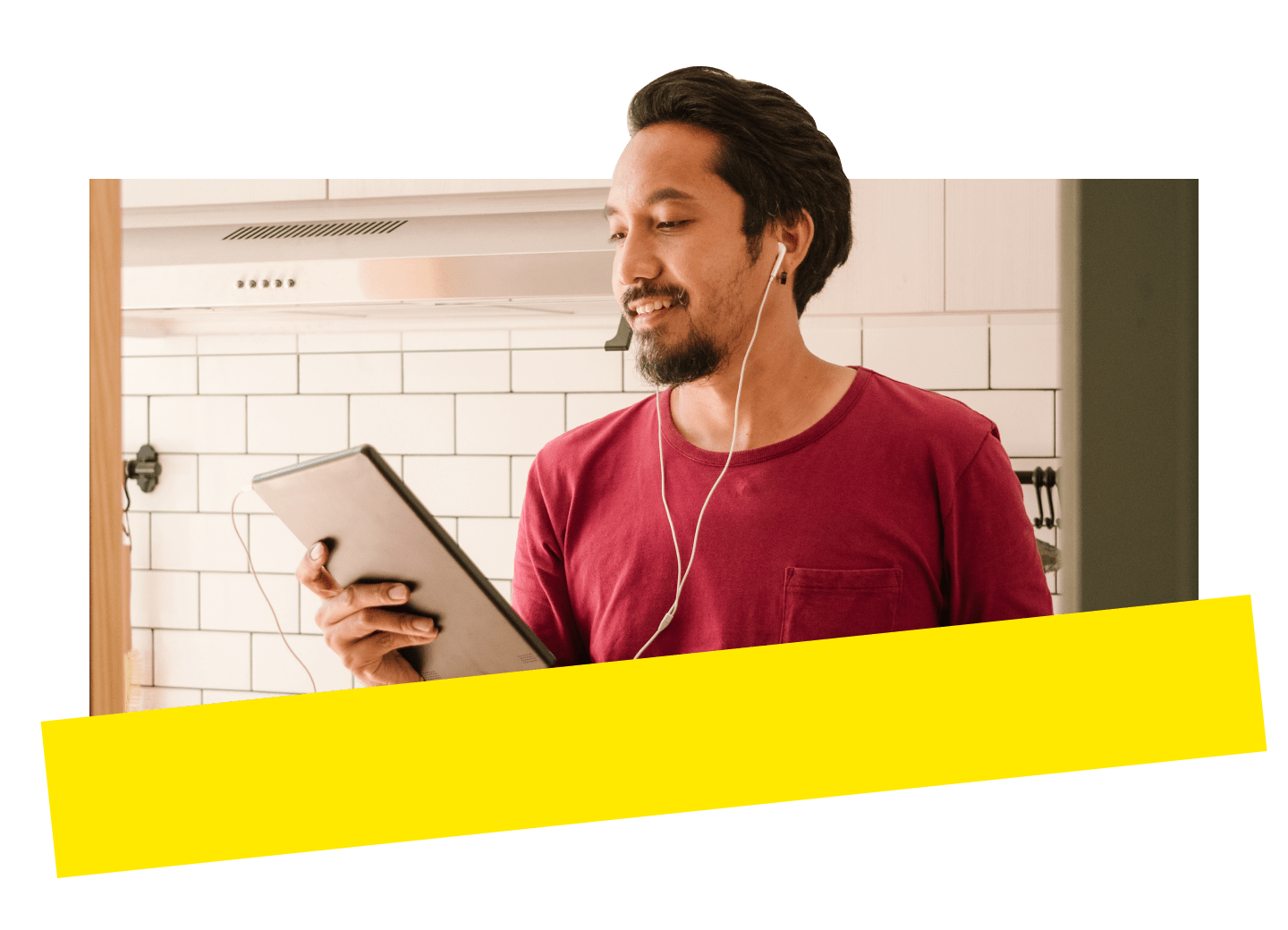 A casually dressed man smiling while attending a GoToConnect call on his tablet from his kitchen.