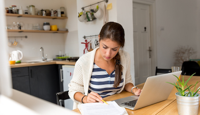 Woman working from home kitchen with laptop