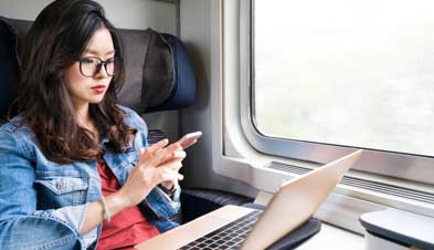 Woman working on a train with laptop and phone